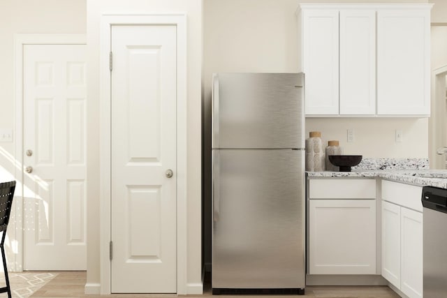 kitchen with light stone counters, stainless steel appliances, light wood-style floors, and white cabinetry