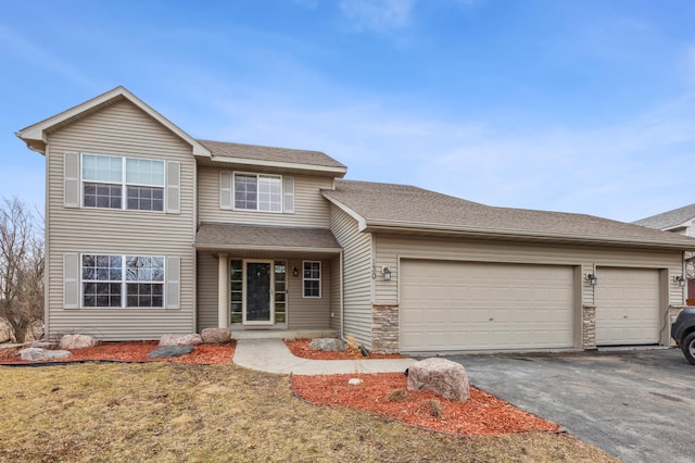 traditional-style home featuring aphalt driveway, stone siding, roof with shingles, and an attached garage