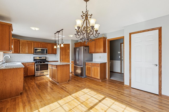 kitchen with a kitchen island, light wood-style flooring, stainless steel appliances, and a sink