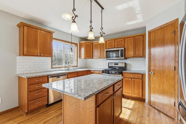 kitchen featuring a sink, brown cabinetry, light wood finished floors, and stainless steel appliances