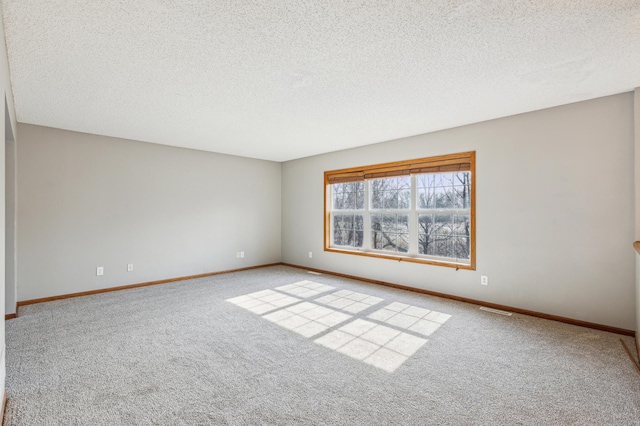 empty room featuring carpet flooring, a textured ceiling, baseboards, and visible vents