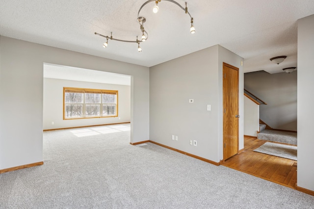 spare room with stairway, carpet flooring, baseboards, and a textured ceiling