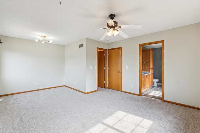 unfurnished room with a ceiling fan, visible vents, baseboards, a textured ceiling, and carpet flooring