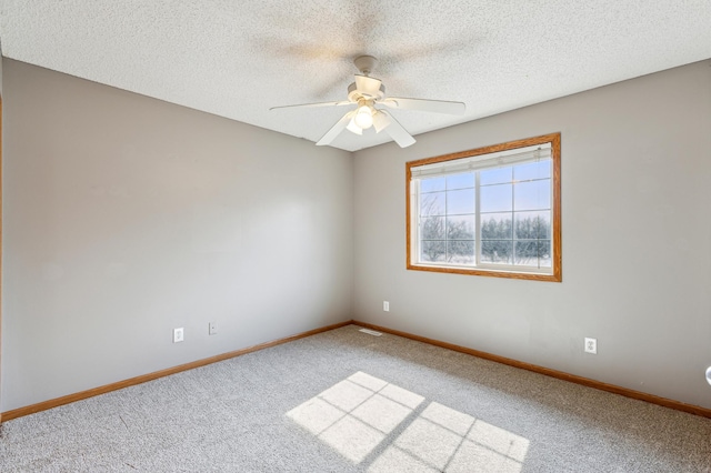 carpeted spare room featuring ceiling fan, baseboards, and a textured ceiling