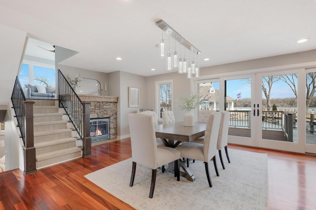 dining area featuring plenty of natural light, a stone fireplace, and wood finished floors