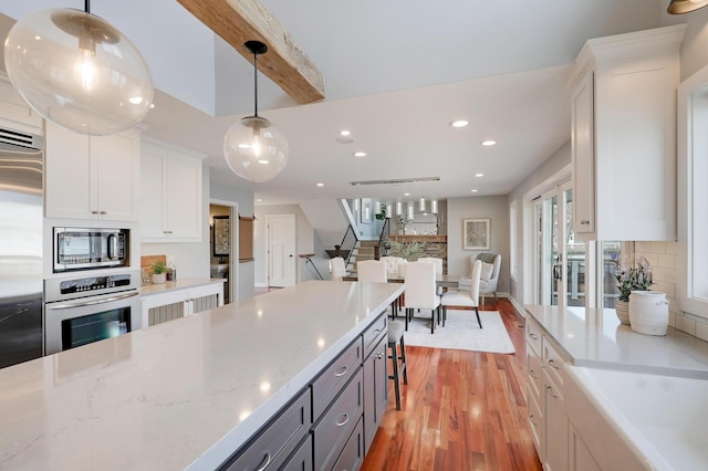 kitchen with light wood-type flooring, built in appliances, backsplash, and white cabinets