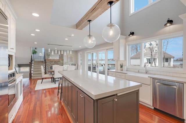 kitchen with a sink, appliances with stainless steel finishes, light wood-style flooring, and white cabinetry