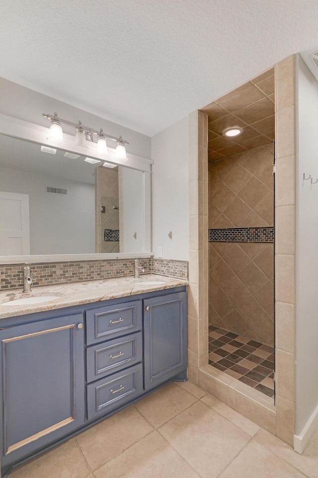 bathroom featuring double vanity, a shower stall, backsplash, and a sink