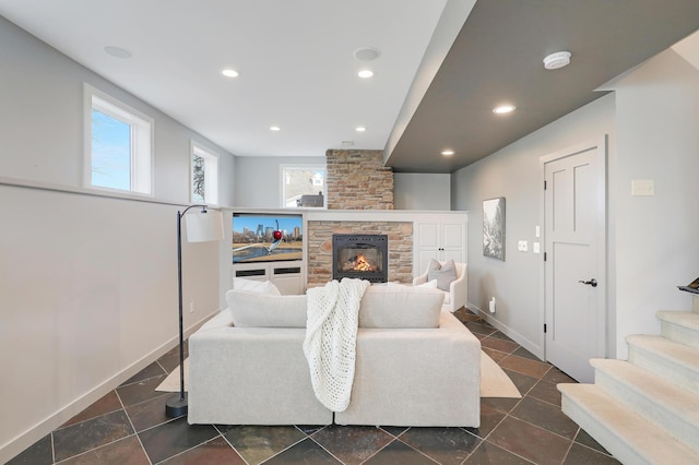 living area with a wealth of natural light, a stone fireplace, and recessed lighting