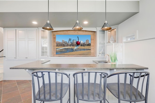 kitchen featuring glass insert cabinets, a kitchen breakfast bar, pendant lighting, and white cabinetry