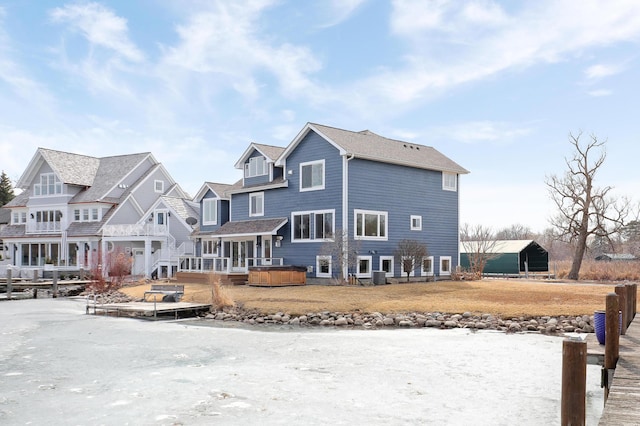 rear view of house featuring a wooden deck and a hot tub