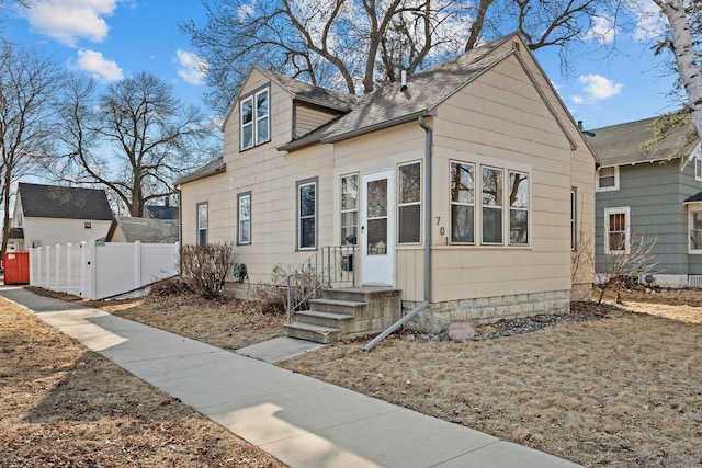 view of front facade featuring a shingled roof and fence