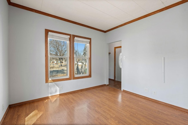 unfurnished room featuring baseboards, wood finished floors, and crown molding