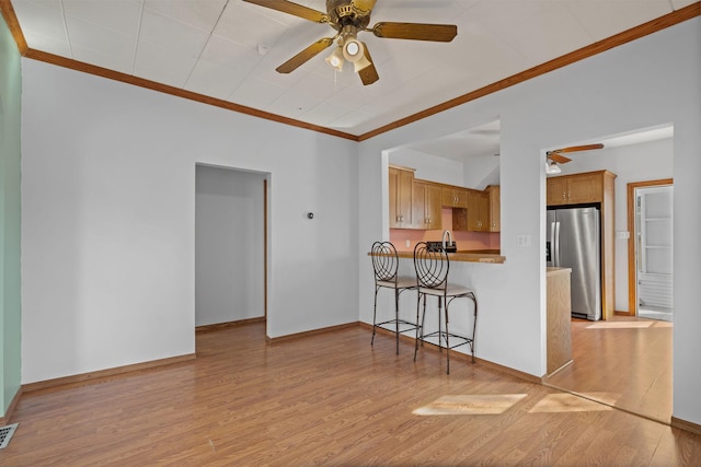 living area with visible vents, baseboards, ceiling fan, ornamental molding, and light wood-style flooring