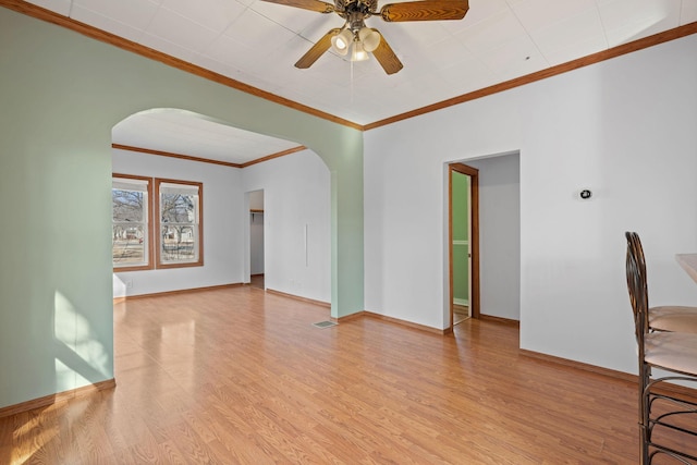 interior space featuring visible vents, baseboards, ceiling fan, wood finished floors, and arched walkways