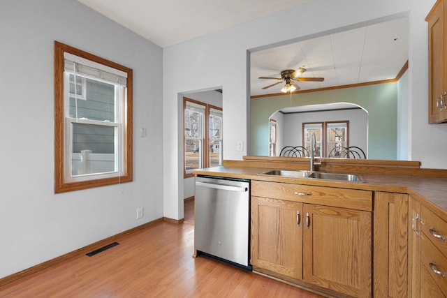 kitchen featuring visible vents, light wood finished floors, arched walkways, a sink, and dishwasher