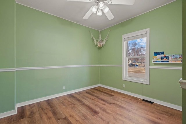 spare room featuring visible vents, wood finished floors, baseboards, and ceiling fan