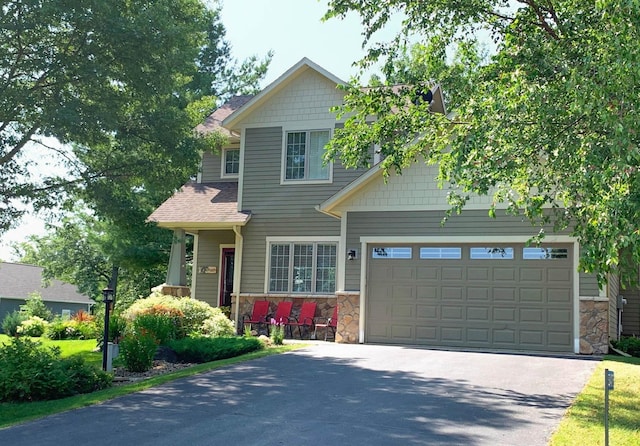 craftsman inspired home with stone siding, driveway, and a garage