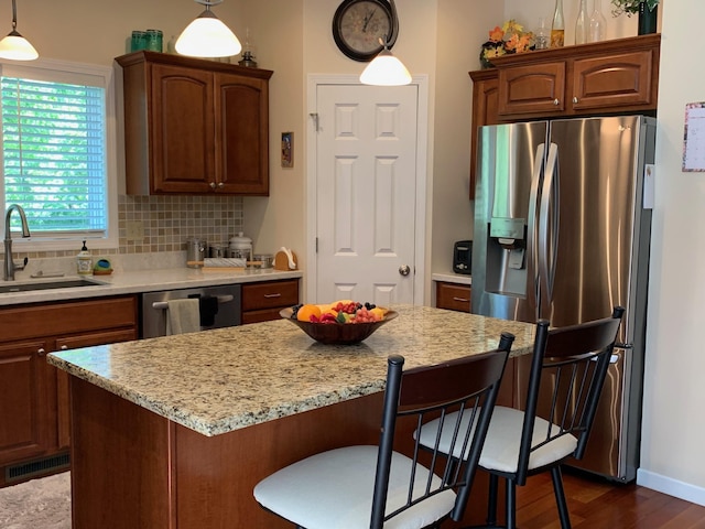 kitchen with visible vents, a breakfast bar area, decorative backsplash, appliances with stainless steel finishes, and a sink