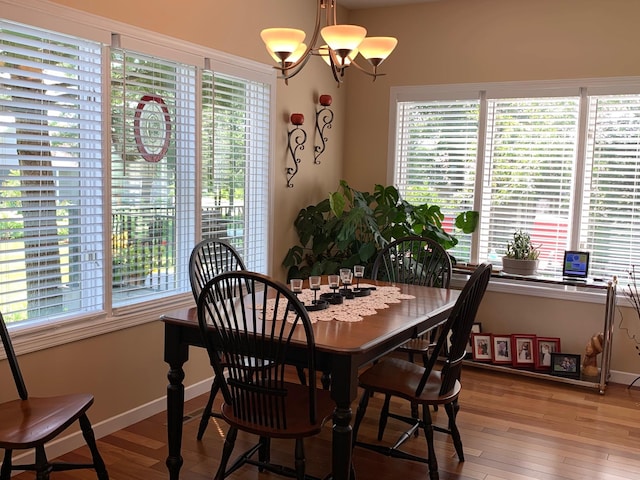 dining area featuring a chandelier, baseboards, and wood finished floors