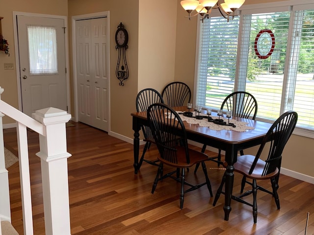 dining space featuring light wood finished floors, baseboards, and an inviting chandelier