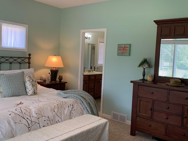 bedroom with visible vents, ensuite bathroom, a sink, carpet flooring, and baseboards