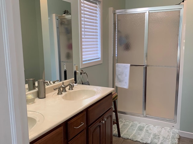 full bathroom featuring a sink, double vanity, and a shower stall