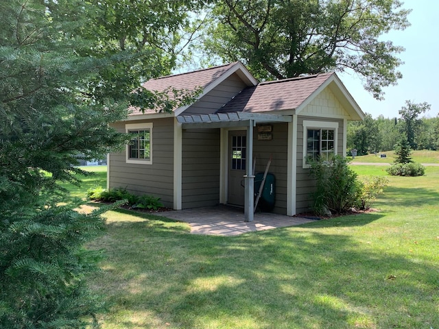 exterior space featuring a patio, a shingled roof, and a front yard