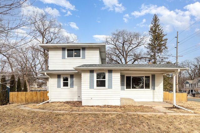 traditional home featuring roof with shingles and fence