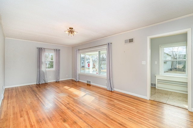 empty room with light wood-type flooring, visible vents, and ornamental molding