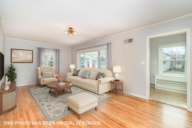 living area featuring plenty of natural light, wood finished floors, visible vents, and baseboards