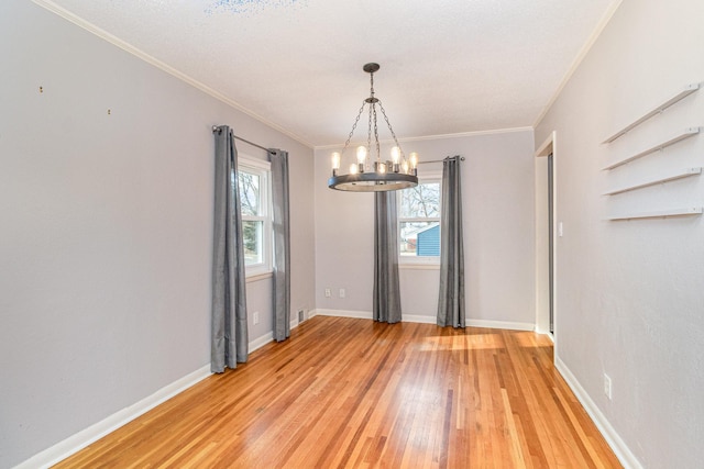 unfurnished room with a chandelier, light wood finished floors, baseboards, and ornamental molding