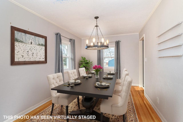 dining space featuring baseboards, an inviting chandelier, ornamental molding, and light wood finished floors