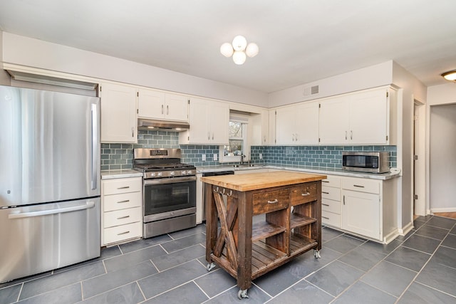 kitchen featuring visible vents, under cabinet range hood, butcher block countertops, appliances with stainless steel finishes, and white cabinetry