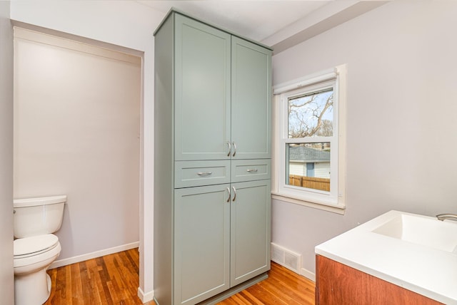 bathroom featuring visible vents, baseboards, toilet, and wood finished floors