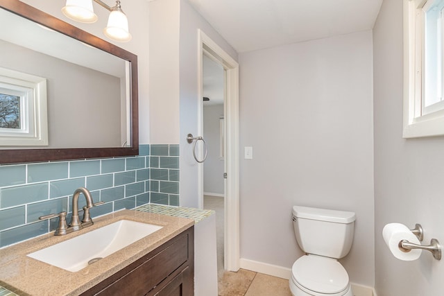 bathroom featuring vanity, baseboards, tile patterned floors, toilet, and tasteful backsplash