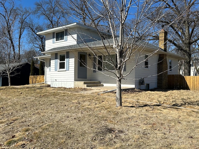 view of front of home with a garage, a chimney, and fence