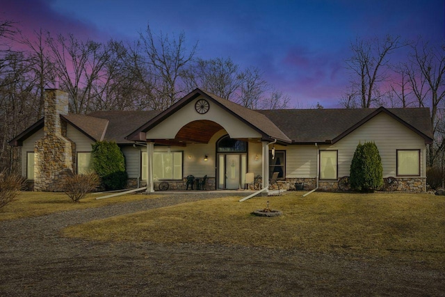 view of front of house featuring a front yard, stone siding, and a chimney