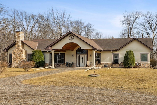 view of front of home with stone siding, a chimney, roof with shingles, and an outdoor fire pit