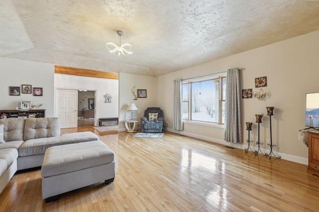 living room with a chandelier, baseboards, lofted ceiling, and light wood-style floors