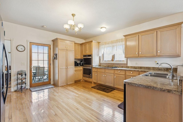 kitchen featuring a notable chandelier, light wood-style flooring, appliances with stainless steel finishes, and a sink