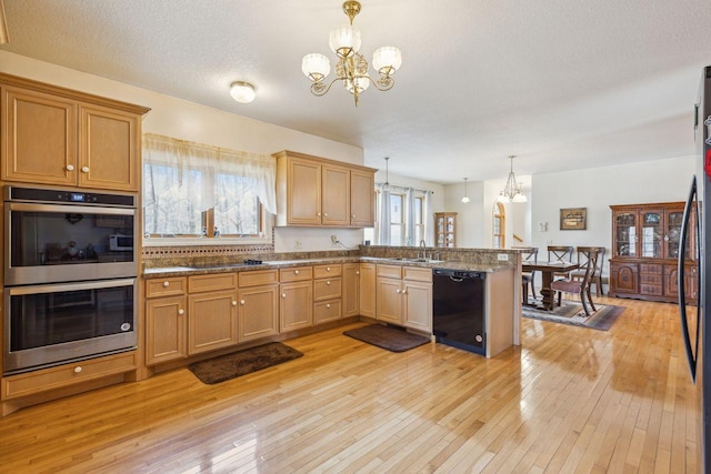 kitchen featuring light wood-type flooring, a notable chandelier, black appliances, and a peninsula