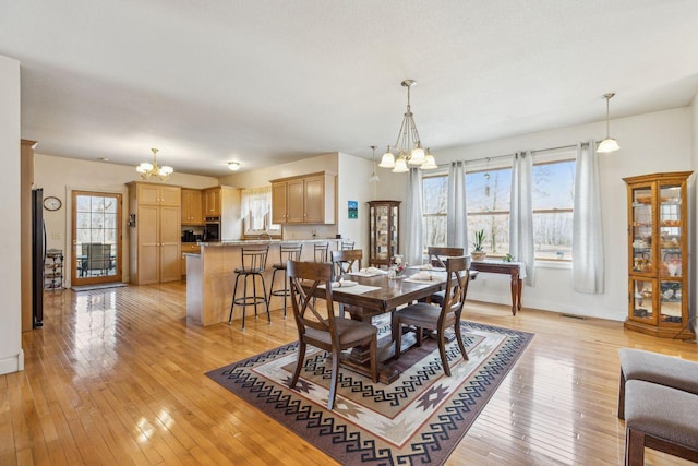 dining room featuring a chandelier, a healthy amount of sunlight, and light wood finished floors