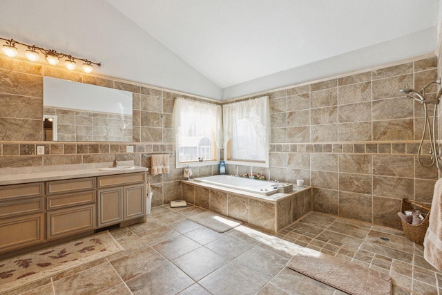 full bath with tile walls, vaulted ceiling, tiled shower, a bath, and vanity