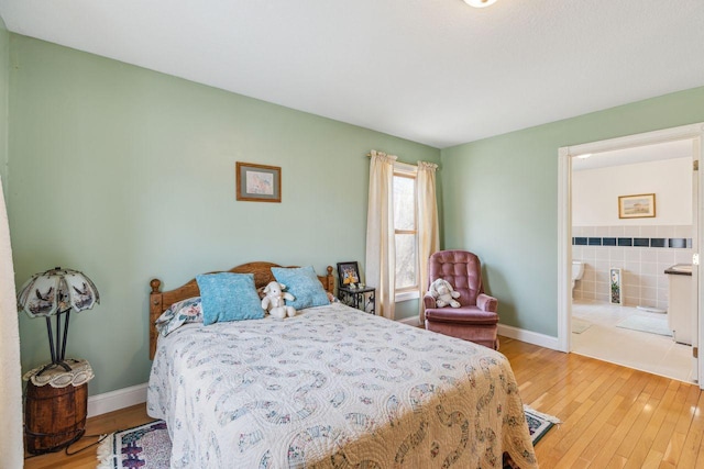 bedroom with baseboards, light wood-type flooring, and connected bathroom