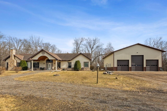 view of front facade featuring a garage, stone siding, and an outbuilding