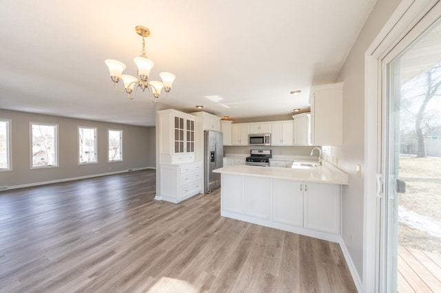 kitchen featuring light wood-style flooring, a sink, open floor plan, stainless steel appliances, and an inviting chandelier