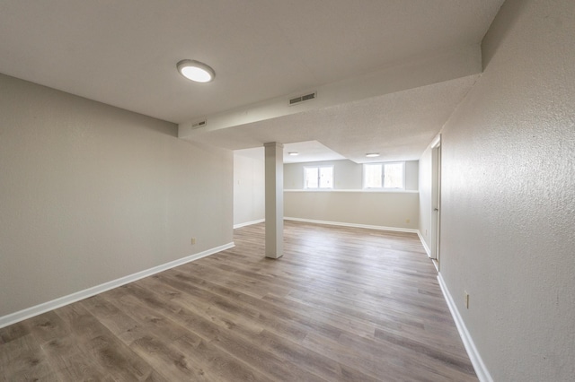 below grade area with visible vents, baseboards, and wood finished floors