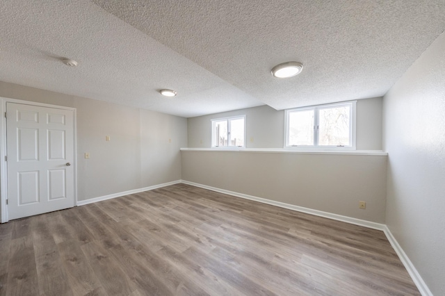 basement with a textured ceiling, baseboards, and wood finished floors