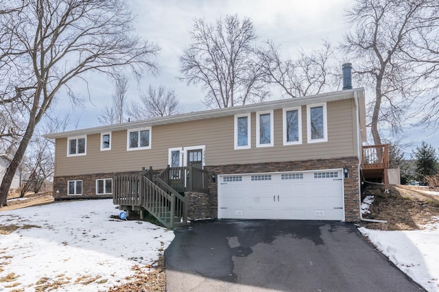 split foyer home with stone siding, stairway, driveway, and an attached garage